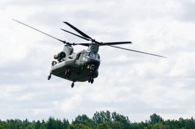 Liepaja, Letonya - 7 Ağustos 2022: Bir Kraliyet Hava Kuvvetleri Chinook Helikopteri uçma potansiyelini, bulutlu gökyüzü arkaplanını sergiliyor