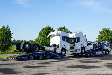 Özel kamyon römorklarıyla yepyeni kamyonlar, satıcılara teslimat, mavi gökyüzü arka planı.