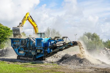 Mobile concrete and reinforced concrete construction debris crushing machine in action, construction debris recycling into finer fractions clipart