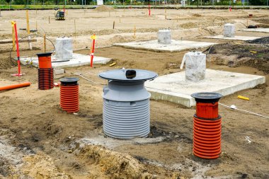 Yeni modern sanayi binasının inşaat sahasında çelik sütunlar için beton zemini, kanalizasyon ve yağmur suyu kuyularının kurulumu