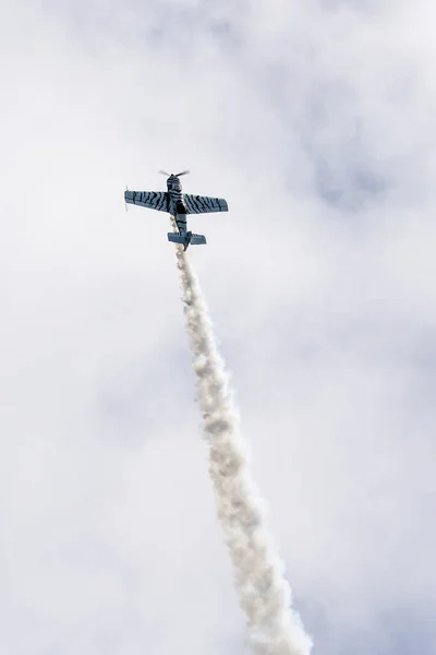 A light sport aircraft flies vertically in a cloudy sky, demonstrates its flying potential before performing aerobatic maneuver stunts