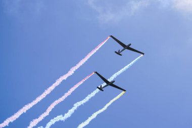 Liepaja, Letonya - 07 Ağustos 2022: Mavi gökyüzünde paralel uçuşta renkli duman izli iki planör yükseliyor