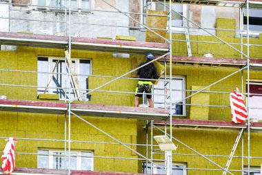Kalın mineral kaya yünü plakalı bir apartmanın dış cephesinde iskele kullanılarak termal yalıtım.