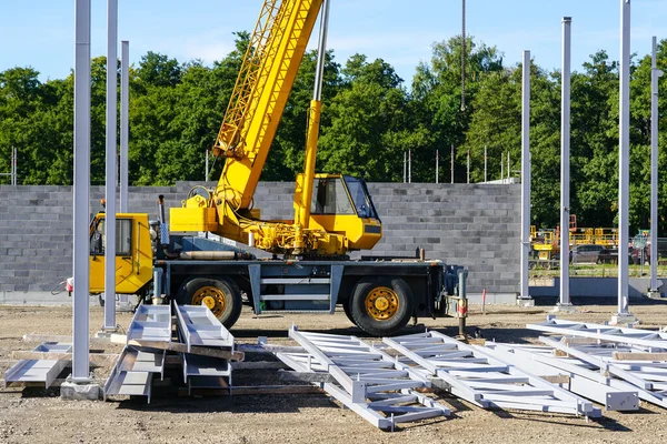 垂直鋼柱 鋼梁と黄色のモバイル油圧伸縮クレーンと新しい近代的な工業ビルの建設現場 — ストック写真