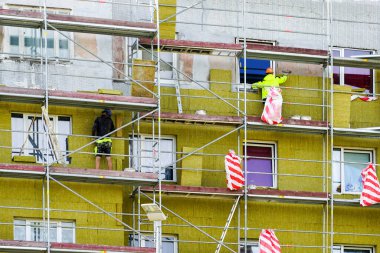 Kalın mineral kaya yünü plakalı bir apartmanın dış cephesinde iskele kullanılarak termal yalıtım.