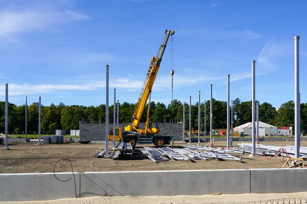 垂直鋼柱 鋼梁と黄色のモバイル油圧伸縮クレーンと新しい近代的な工業ビルの建設現場 — ストック写真