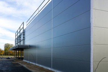 Bitmemiş bir depo binasının gri sandviç maskesini, mavi gökyüzü arka planını.