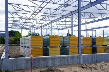 Çelik yapı iskeleti inşaatı ve yeni bir modern deponun ön cephesi için bir yığın sandviç paneli.