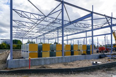 Çelik yapı iskeleti inşaatı ve yeni bir modern deponun ön cephesi için bir yığın sandviç paneli.