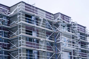Scaffolding around an apartment building under renovation is covered with hoarfrost and snow during winter
