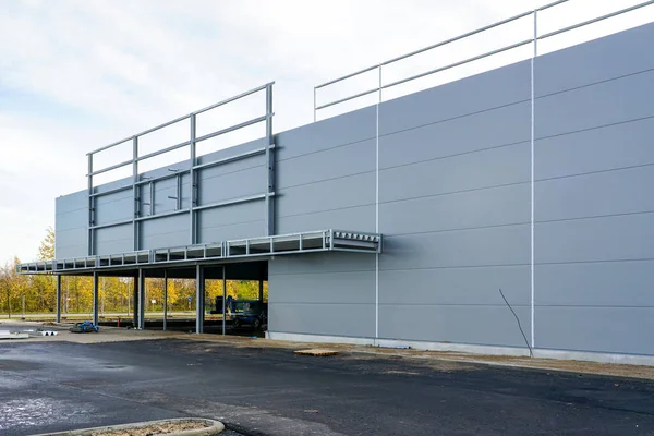 Unfinished modern metal frame warehouse building facade covered with gray thermally insulated sandwich panels