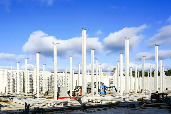 Many white vertical reinforced concrete columns at the construction site of an industrial facility, blue sky background