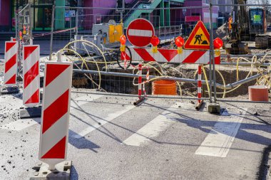 Kırmızı ve beyaz çizgili dikey uyarı kalınlıkları, tabelaları, bariyerleri, geçici metal çitleri, su arıtma sistemi olan sokak onarım alanı.