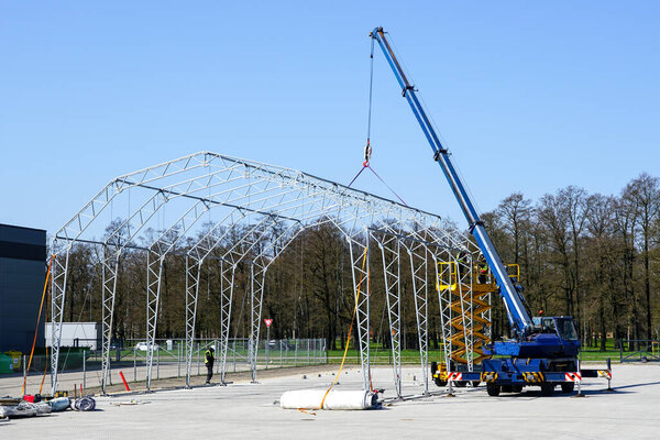 Assembly of the metal frame of the tent storage hangar with the help of a telescopic boom crane and a self propelled scissor lift
