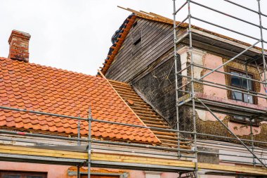 Repair of the facade and roof of a historic house, replacement of clay tiles, facade plaster restoration, wooden netting grid under stucco clipart