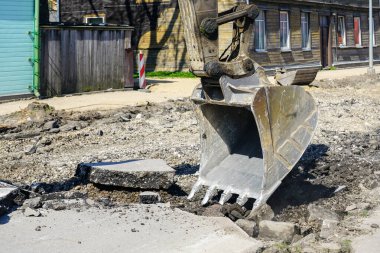 Eski asfalt tabakasını sokak inşaatından önce parçalayan hidrolik kazıcı kovasının yakınlaştırılması