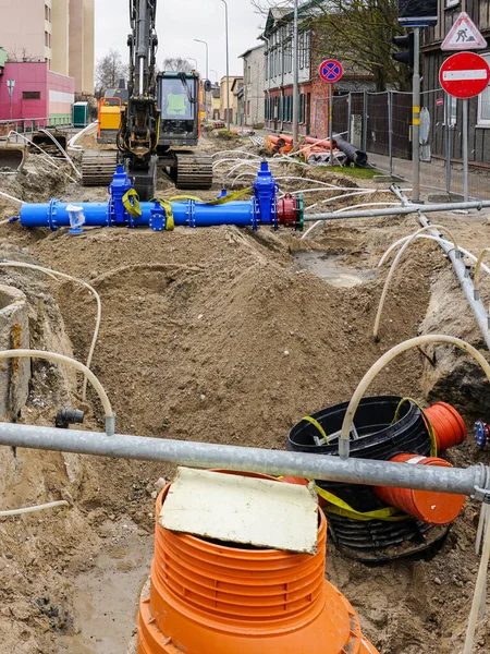 stock image Underground pipe replacement trench on city street, large plastic wells, new drink water pipeline with gate valves