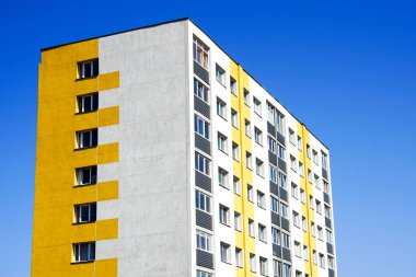 Renkli ve yalıtılmış çok katlı apartman, mavi gökyüzü arka planına karşı.
