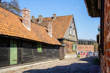 Liepaja 'nın eski ahşap evleri, kil kiremit çatıları, bir sürü bacası, mavi gökyüzü arka planı olan manzarası.