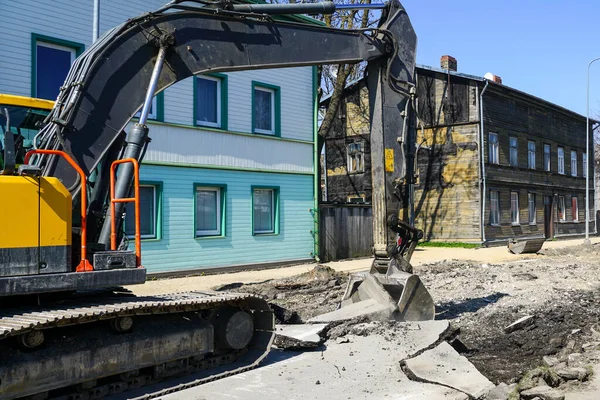 stock image A large crawler excavator with a bucket dismantle the old layer of asphalt before the reconstruction of the city street