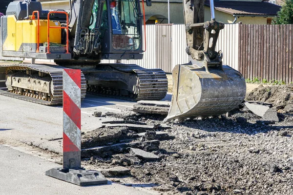 Bir kova ile büyük bir sürüngen kazıcı şehrin yeniden inşasından önce eski asfalt katmanını söker