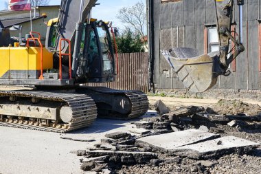 Bir kova ile büyük bir sürüngen kazıcı şehrin yeniden inşasından önce eski asfalt katmanını söker