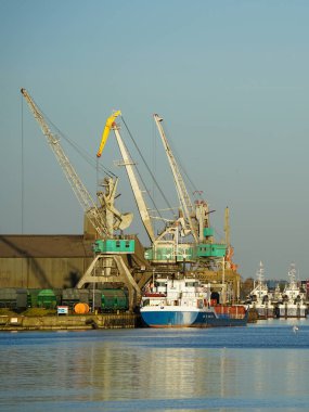 Gün batımında gemi ve vinçlerle liman manzarası, Liepaja, Letonya, Baltık denizi