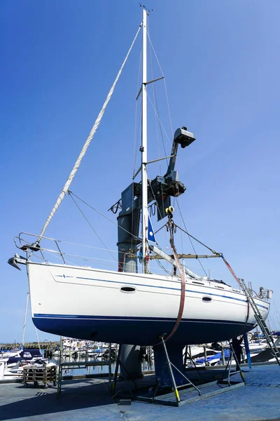 stock image The yacht lifted ashore by a sailboat lift for the repair and maintenance of the underwater part of the hull