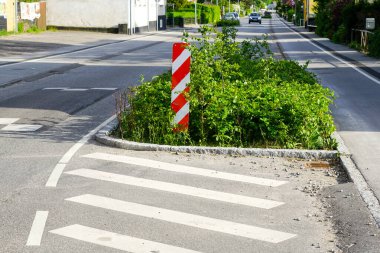 Kentte, dikey kırmızı ve beyaz çizgili uyarı işareti, yağmur bahçeleri, Danimarka ve Avrupa 'da zorunlu hız azaltımı için caddenin kenarında yeşillik var.