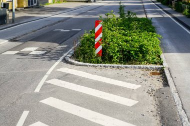 Kentte, dikey kırmızı ve beyaz çizgili uyarı işareti, yağmur bahçeleri, Danimarka ve Avrupa 'da zorunlu hız azaltımı için caddenin kenarında yeşillik var.