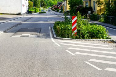 Kentte, dikey kırmızı ve beyaz çizgili uyarı işareti, yağmur bahçeleri, Danimarka ve Avrupa 'da zorunlu hız azaltımı için caddenin kenarında yeşillik var.