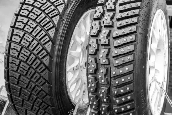 Two types of modern rally tires, studded winter snow and ice tire with big studs and asymmetric gravel tire