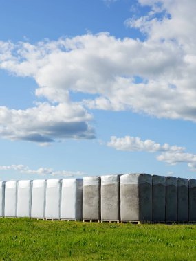 Bir çok büyük polyethylene turba poşetleri ahşap paletler üzerinde bir fabrikanın üretim alanı yakın peatbataklık altında mavi bir gökyüzü altında, turba çıkarma