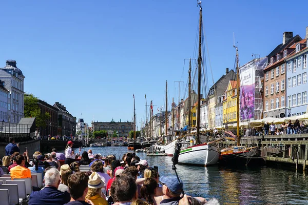 Kopenhag, Danimarka - 30 Mayıs 2023 Nyhavn Rıhtımı, birçok insanla birlikte kanal turu teknesinin renkli manzarası, güneşli mavi gökyüzü.