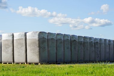Turba çıkarma, mavi gökyüzünün altındaki turba bataklığına yakın bir fabrikanın üretim alanında ahşap paletler üzerinde birçok büyük polietilen turba torbaları.