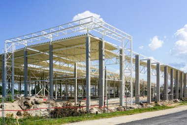Tamamlanmamış çelik çerçeve yapısı güçlendirilmiş beton destekli çelik çatılı, mavi gökyüzü arka planlı