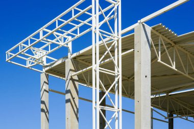 Tamamlanmamış ticari yapı çelik ve beton çerçeve ön cephe parçası mavi gökyüzü, kıvrımlı metal çatı