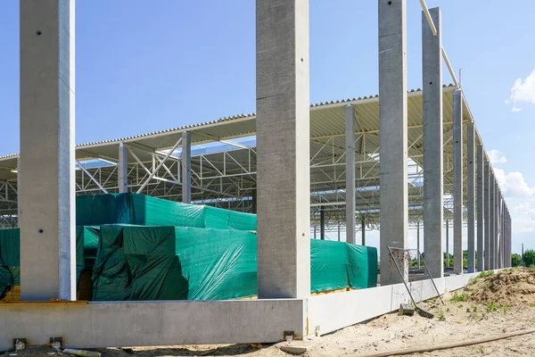 Reinforced concrete supports and foundation blocks of unfinished commercial building, steel frame structure, corrugated metal roof