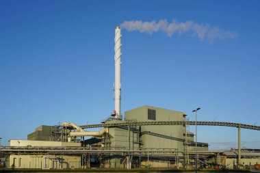 Yüksek buhar bacası, ahşap çip güç santrali, mavi gökyüzü arka planı ile büyük modern biyokütle kojenerasyon ahşap güç santrali dış görünüm
