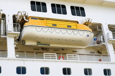 Asılı cankurtaran botu ve kurtarma botu olan büyük beyaz bir yolcu gemisinin yan görüntüsü.