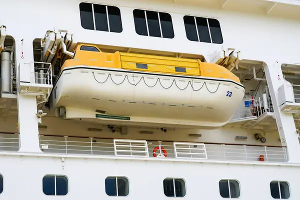 Side view of a large white cruise ship with hanging lifeboat, emergency rescue boat