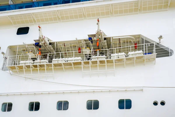 Side view of a large white cruise ship with many hanging life rafts, emergency rescue rafts, self inflating life rafts