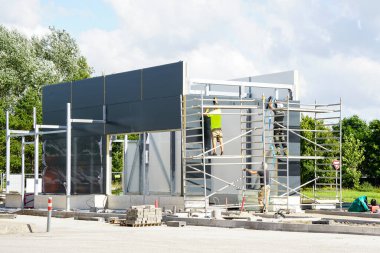 Termal yalıtımlı beton tabanı ve bitmemiş sandviç panelleri olan, modern, tamamlanmamış bir araba yıkama binasının çelik iskeleti.