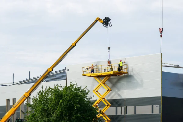 stock image Sandwich panels wall assembly using telescopic boom crane and yellow self propelled scissor lift platform