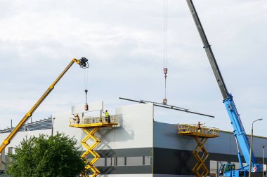 Sandviç paneli duvarları ve çatısı iki teleskopik flok vinç ve iki kendinden itişli makas kaldıracı kullanarak monte edildi.