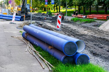 Replacement of underground water supply and sewer pipes in city street, new blue thick plastic water supply pipes in foreground clipart