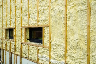 The facade of the residential house sprayed with a layer of polyurethane thermal insulation foam before siding with wooden planks clipart