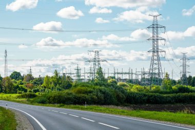 Yüksek voltajlı elektrik hatlarına sahip endüstriyel doğa manzarası iletim direkleri, yüksek voltaj alt istasyonu, beyaz bulutlu mavi gökyüzü