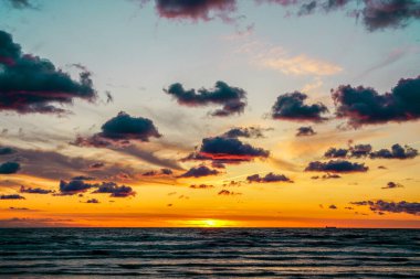 Baltık Denizi kıyısında çok renkli altın bir gün batımı, deniz kıyısında çok renkli altın bir gün batımı, koyu tüylü kümülüs bulutları.