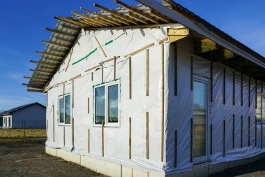 Tamamlanmamış, tek katlı ahşap çerçeveli ev cepheyi bitirmeden önce, mavi gökyüzü arka planı